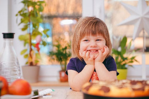 Wie kann ich Kinder in der Küche beschäftigen? Ein lächelndes Kind ist abgebildet.